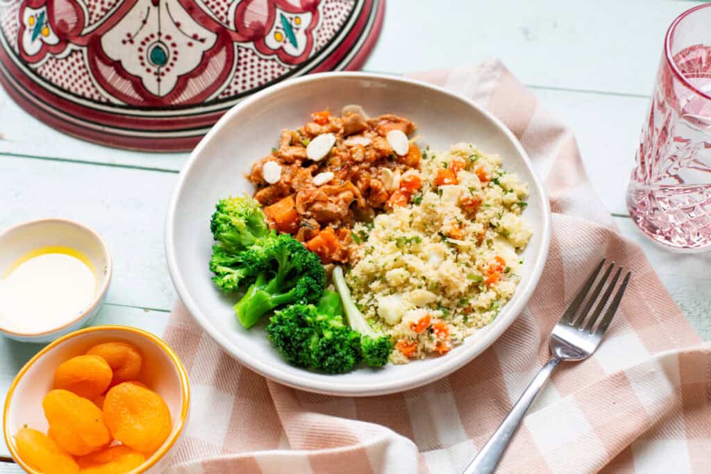 Photo of chicken & apricot tagine, served with couscous and a side of broccoli.