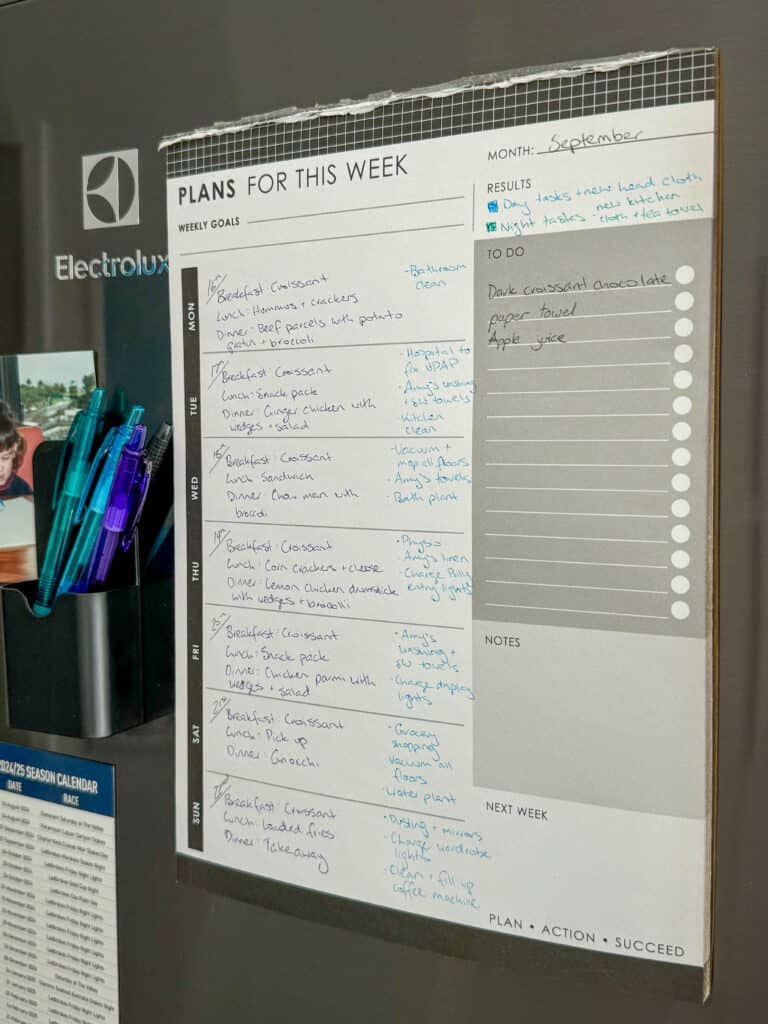 Amy's paper planner stuck onto her gray fridge with notes for the week. Text says "plans for the week" with handwritten notes.