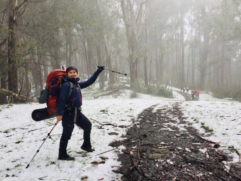 Pei Ting hiking in the snow with a big pack and ski poles