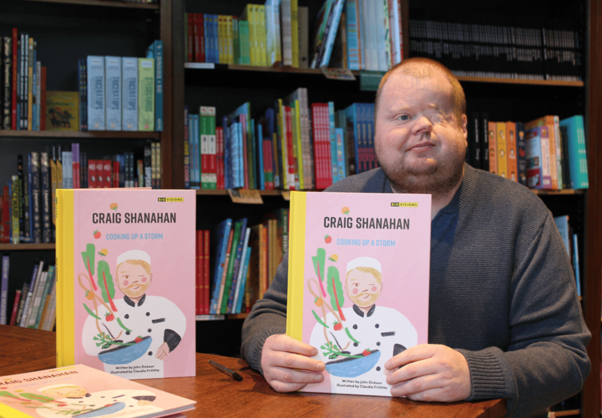 Craig Shanahan holding up his new book, cooking up a storm